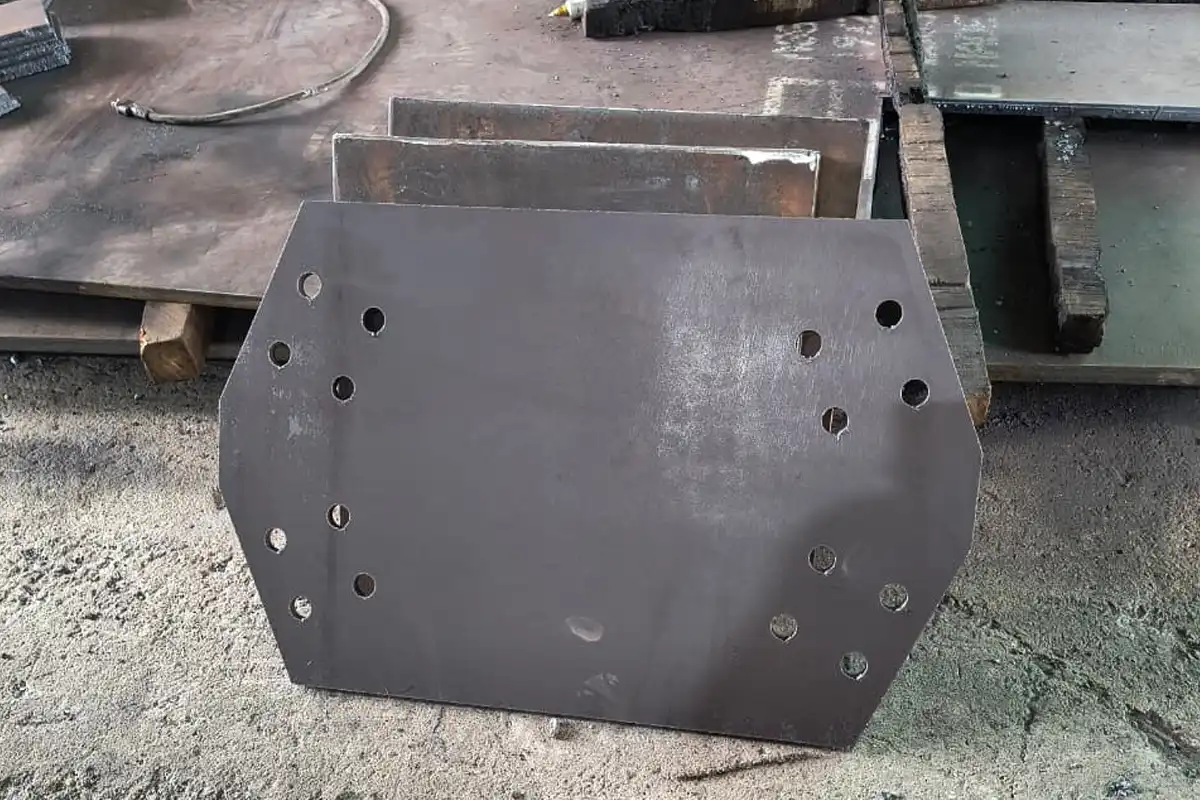 Primer plano de una placa base metálica hexagonal con perforaciones cortadas con extrema precisión por tecnología CNC Láser. Componente clave para estructuras y anclajes industriales. corte láser CNC de alta precisión